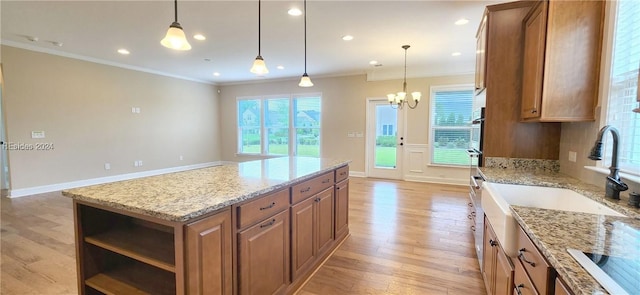 kitchen with pendant lighting, ornamental molding, light stone counters, and a kitchen island