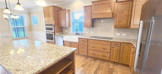 kitchen featuring sink, appliances with stainless steel finishes, ornamental molding, decorative light fixtures, and custom exhaust hood