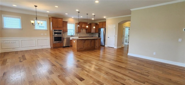 kitchen featuring appliances with stainless steel finishes, decorative light fixtures, a center island, crown molding, and light hardwood / wood-style flooring