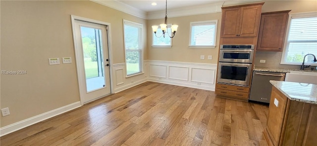 kitchen featuring sink, stainless steel appliances, light stone counters, light hardwood / wood-style floors, and decorative light fixtures