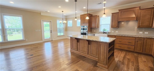 kitchen featuring crown molding, a kitchen island, sink, and pendant lighting