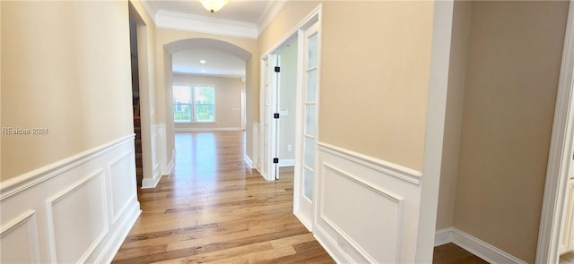 hall with ornamental molding and light hardwood / wood-style floors