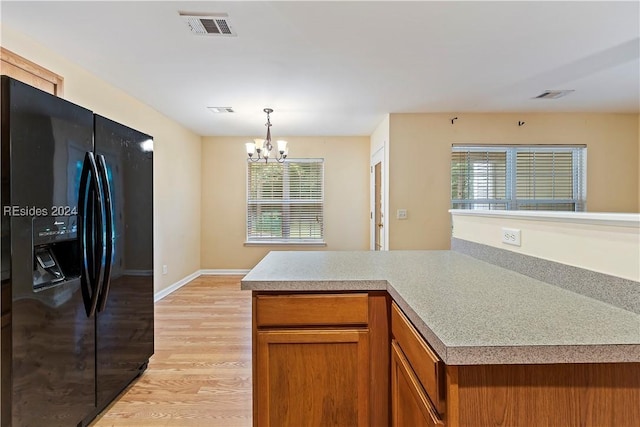 kitchen with pendant lighting, black refrigerator with ice dispenser, a chandelier, and light wood-type flooring