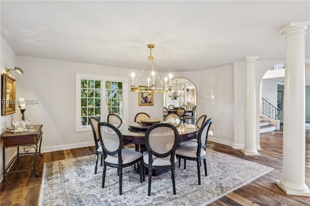 dining space with dark hardwood / wood-style flooring, decorative columns, and an inviting chandelier