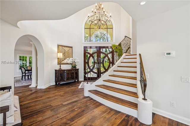 entryway with a towering ceiling, dark hardwood / wood-style floors, and a chandelier