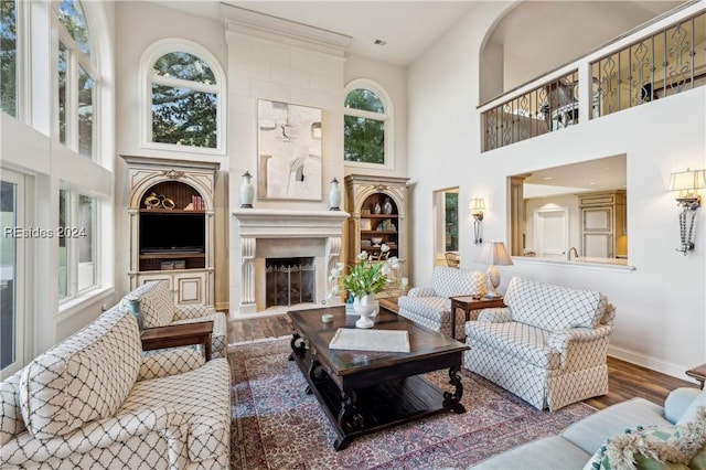 living room with hardwood / wood-style flooring, a fireplace, and a high ceiling