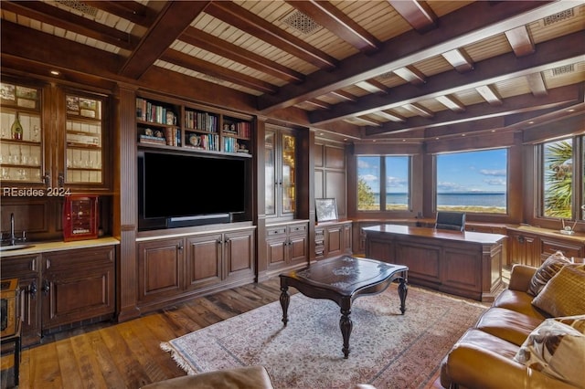 living room featuring beam ceiling, dark wood-type flooring, wooden ceiling, and indoor bar