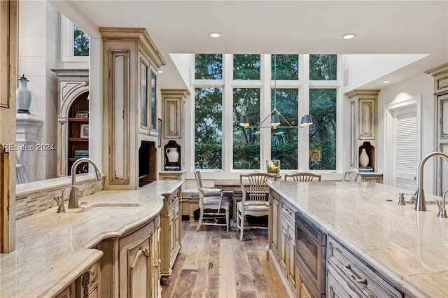 kitchen featuring light hardwood / wood-style floors, beverage cooler, light stone countertops, and sink