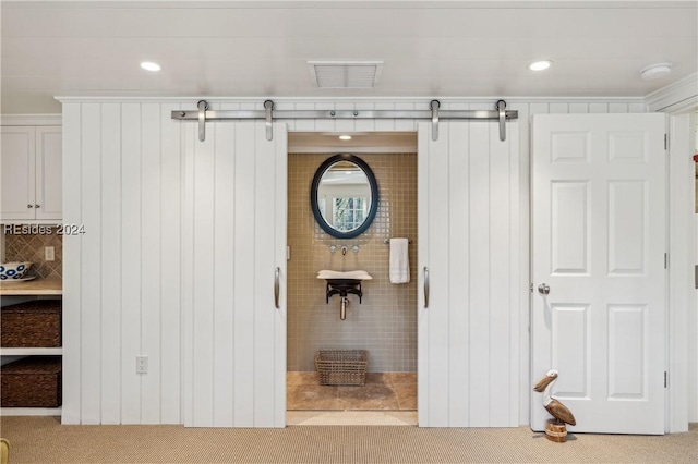 interior space with ornamental molding, a barn door, and carpet flooring