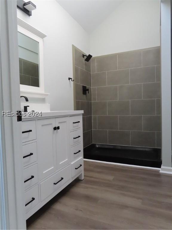 bathroom featuring tiled shower, vanity, and hardwood / wood-style floors