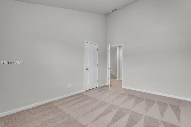 carpeted empty room featuring a high ceiling