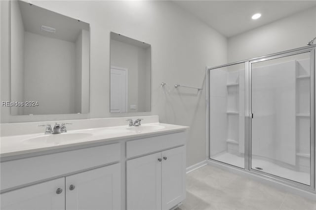 bathroom with a shower with door, vanity, and tile patterned floors