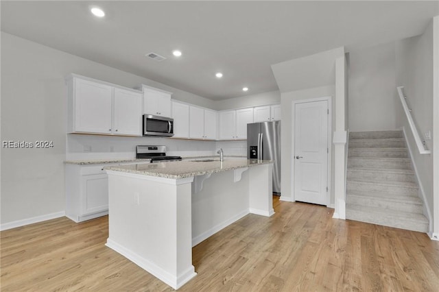 kitchen featuring white cabinetry, appliances with stainless steel finishes, an island with sink, and light wood-type flooring