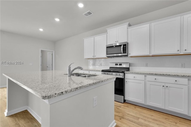 kitchen featuring backsplash, stainless steel appliances, an island with sink, and white cabinets