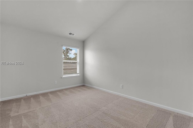 carpeted spare room featuring vaulted ceiling