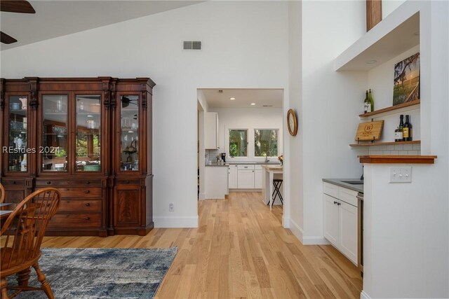 dining room with ceiling fan, high vaulted ceiling, and light wood-type flooring