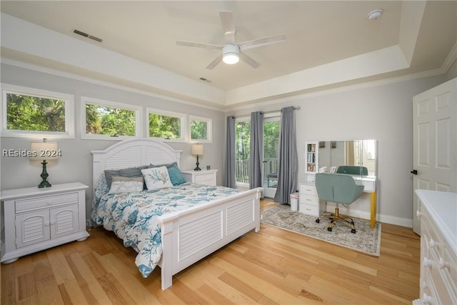 bedroom with a raised ceiling, light wood-type flooring, access to outside, and ceiling fan