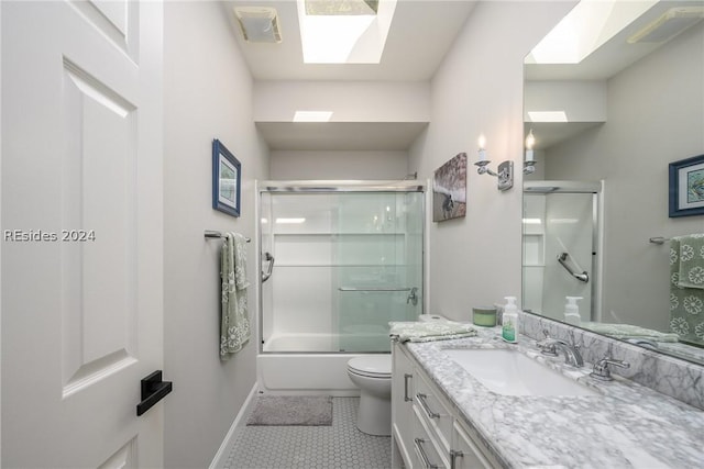 full bathroom featuring tile patterned flooring, a skylight, bath / shower combo with glass door, vanity, and toilet