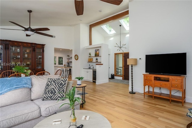 living room featuring light hardwood / wood-style flooring, ceiling fan, a skylight, high vaulted ceiling, and beverage cooler