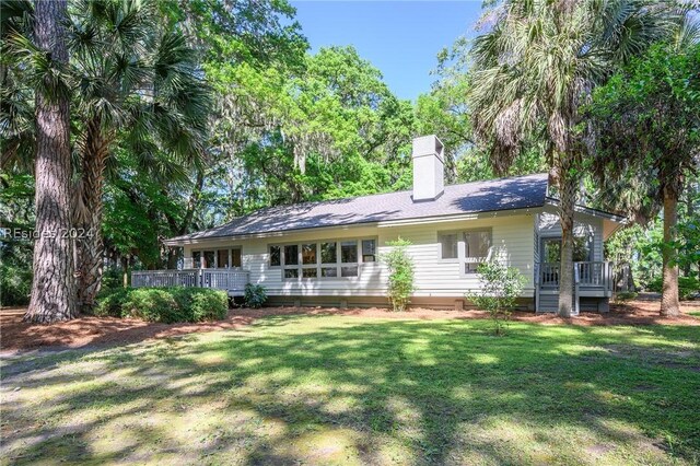 back of property featuring a wooden deck and a yard