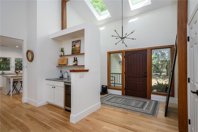 entryway with wine cooler, light hardwood / wood-style flooring, high vaulted ceiling, and a healthy amount of sunlight