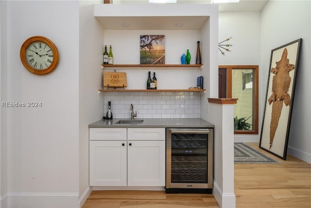 bar with sink, light hardwood / wood-style flooring, wine cooler, tasteful backsplash, and white cabinets