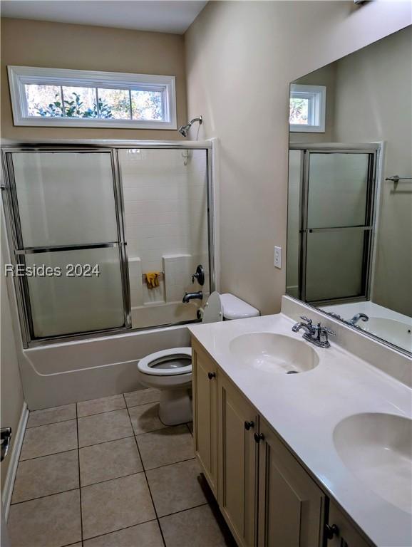 full bathroom featuring enclosed tub / shower combo, a wealth of natural light, tile patterned floors, and toilet