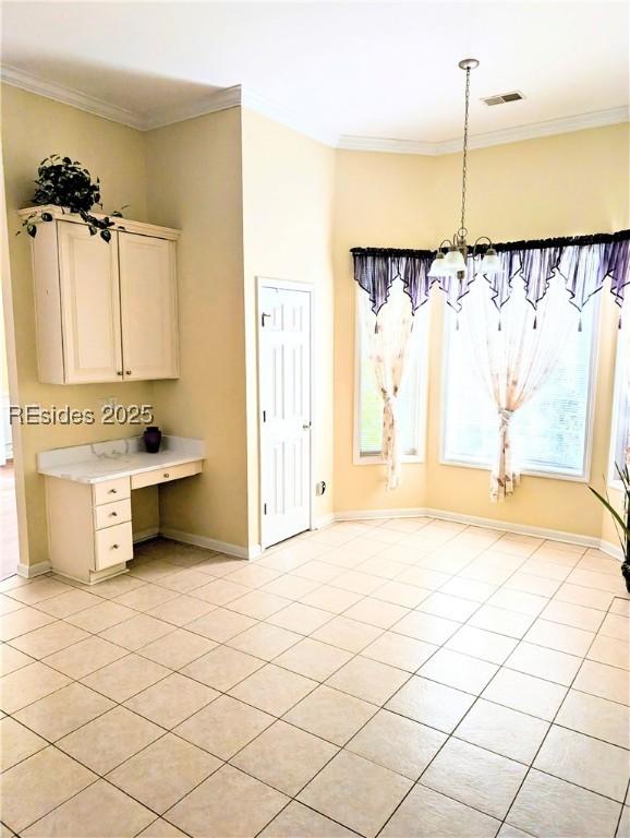 unfurnished dining area featuring light tile patterned floors, crown molding, and a chandelier