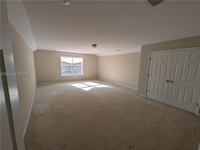 unfurnished room with light colored carpet and vaulted ceiling