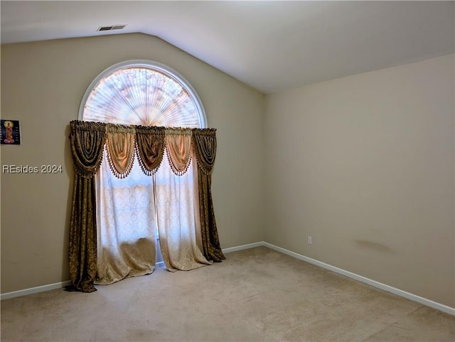 carpeted empty room featuring vaulted ceiling