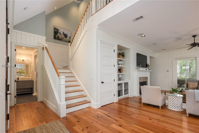 interior space featuring ceiling fan, ornamental molding, a fireplace, and light wood-type flooring