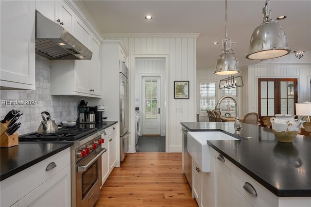 kitchen with high end appliances, pendant lighting, crown molding, and white cabinetry