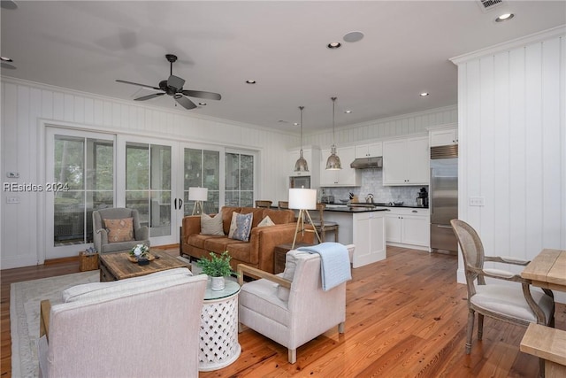 living room featuring ceiling fan, ornamental molding, and light wood-type flooring