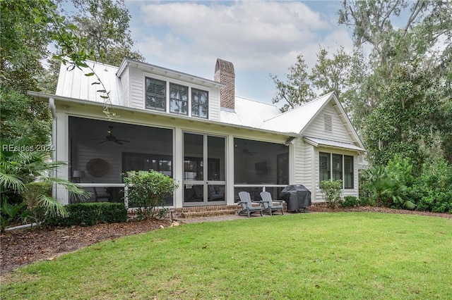 rear view of property featuring ceiling fan, a yard, and a sunroom