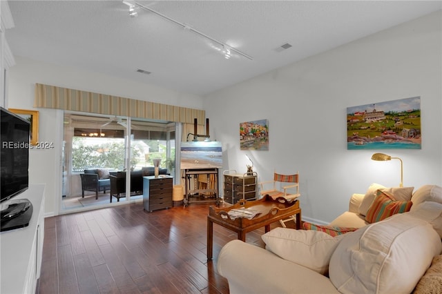 living room with rail lighting, dark hardwood / wood-style floors, and a textured ceiling