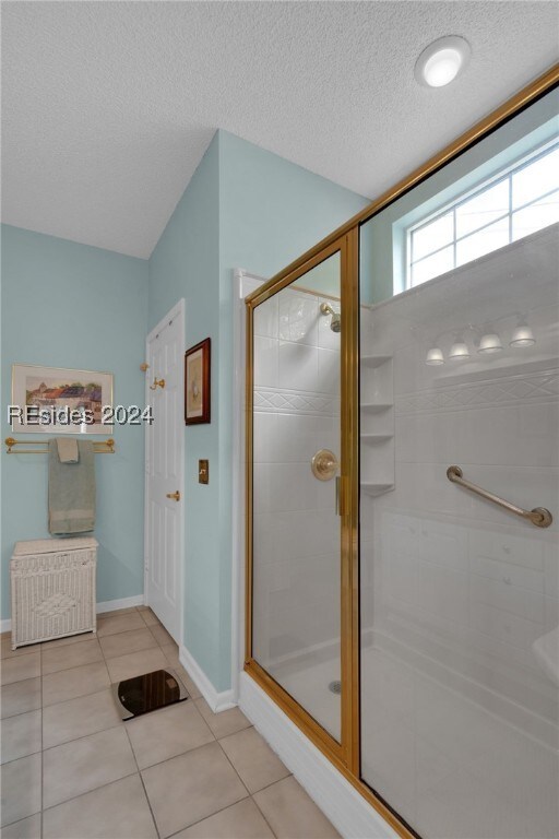 bathroom with tile patterned flooring, a textured ceiling, and a shower with shower door