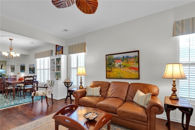 living room with ceiling fan with notable chandelier and dark hardwood / wood-style floors