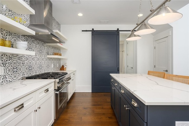 kitchen with white cabinetry, hanging light fixtures, high end stainless steel range, a barn door, and wall chimney exhaust hood