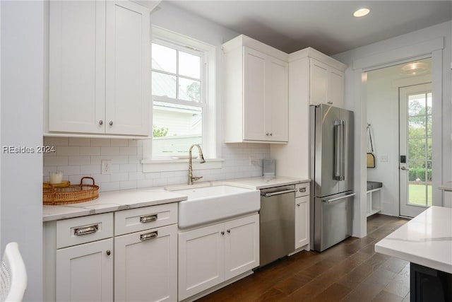 kitchen with sink, stainless steel appliances, light stone counters, tasteful backsplash, and white cabinets