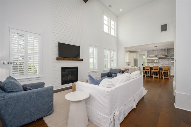 living room with a large fireplace, dark hardwood / wood-style floors, and a high ceiling