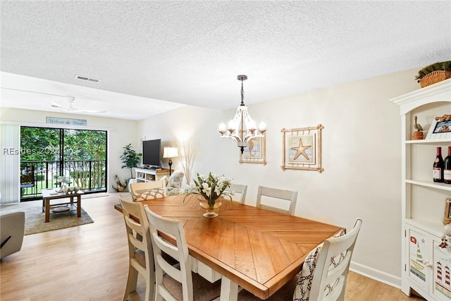 dining space with a chandelier, light hardwood / wood-style flooring, and a textured ceiling