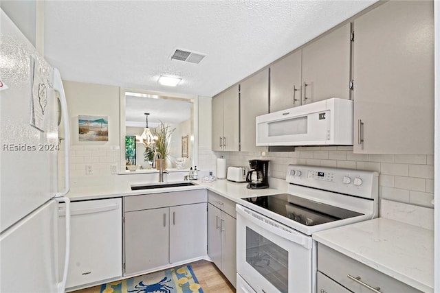 kitchen featuring sink, backsplash, hanging light fixtures, white appliances, and a textured ceiling