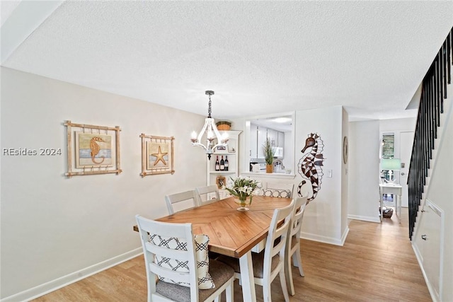 dining space with a chandelier, a textured ceiling, and light wood-type flooring