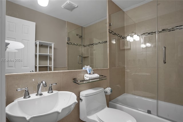 full bathroom featuring tasteful backsplash, bath / shower combo with glass door, sink, and toilet