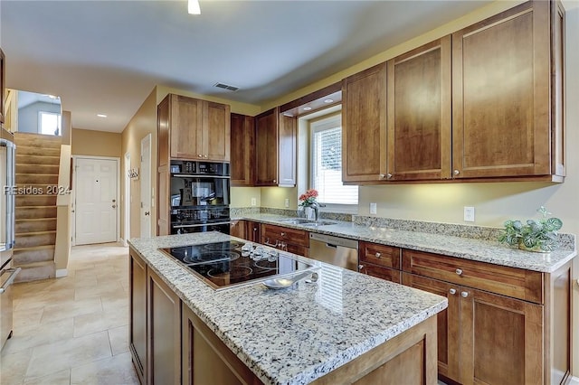 kitchen featuring light tile patterned flooring, a kitchen island, light stone counters, and black appliances