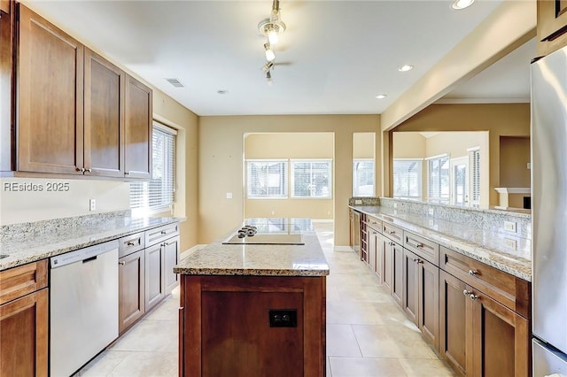 kitchen featuring a kitchen island, light stone countertops, appliances with stainless steel finishes, and track lighting