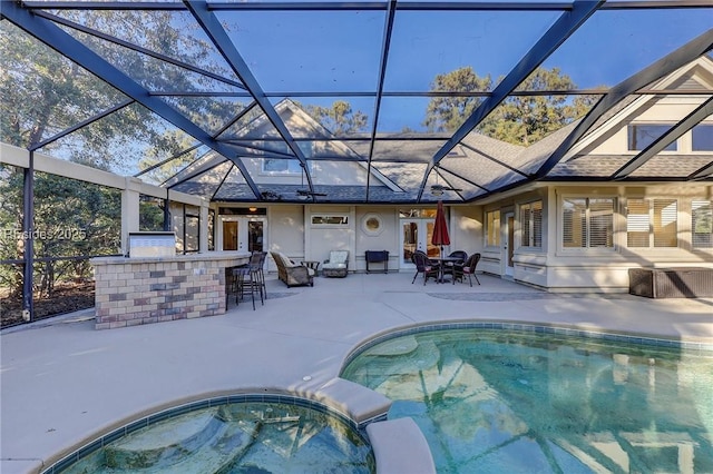 view of swimming pool featuring an in ground hot tub, exterior bar, glass enclosure, and a patio area