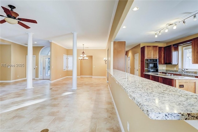 kitchen featuring crown molding, ceiling fan with notable chandelier, light stone countertops, decorative light fixtures, and ornate columns