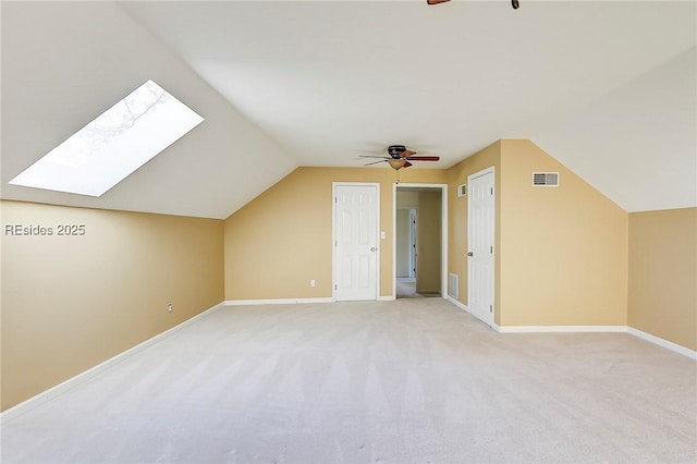 additional living space featuring ceiling fan, lofted ceiling with skylight, and light colored carpet