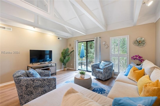 living room featuring vaulted ceiling with beams and light hardwood / wood-style floors